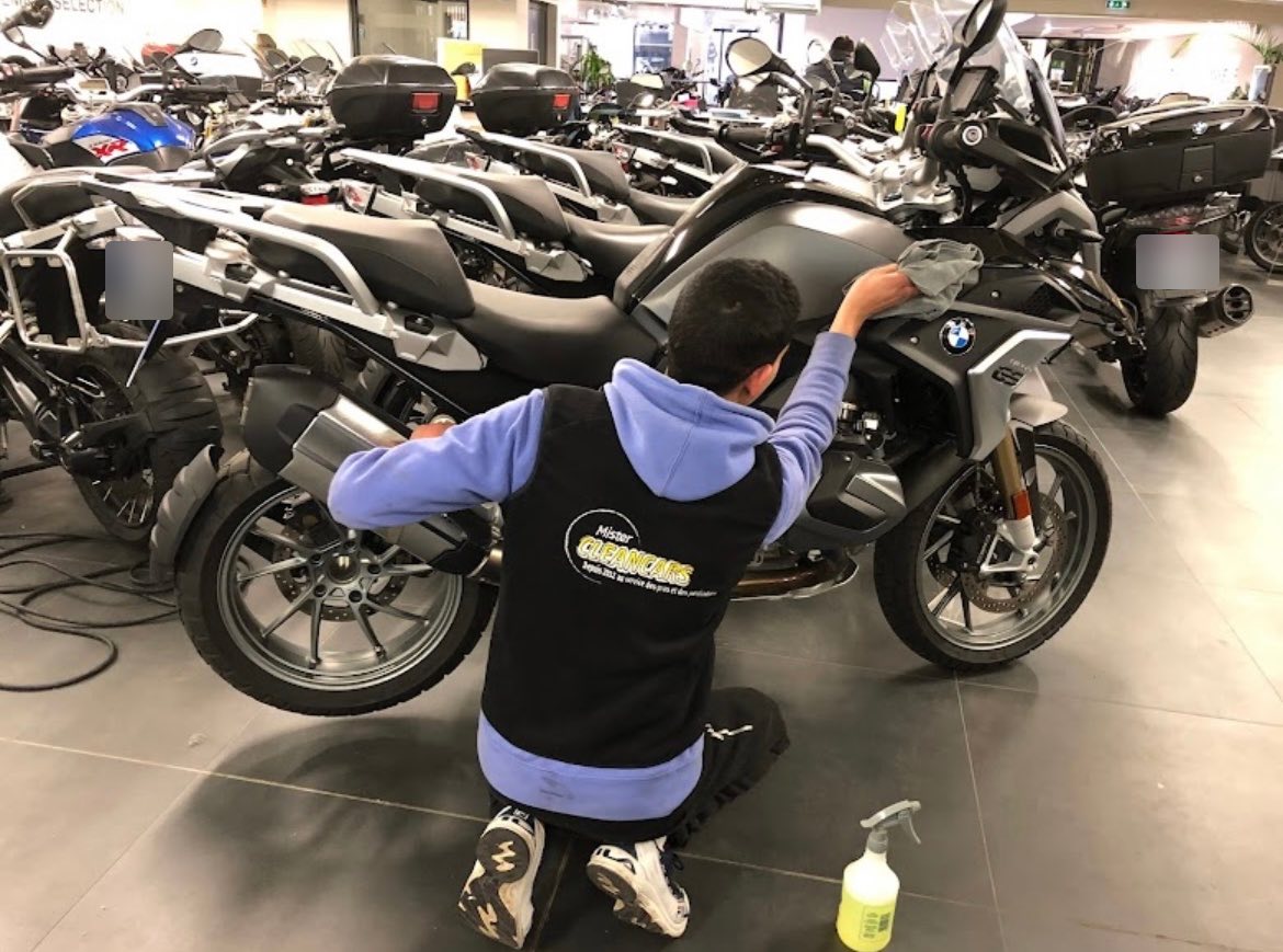 Laveur Mister Clean Cars essuyant une moto BMW GS dans une concession